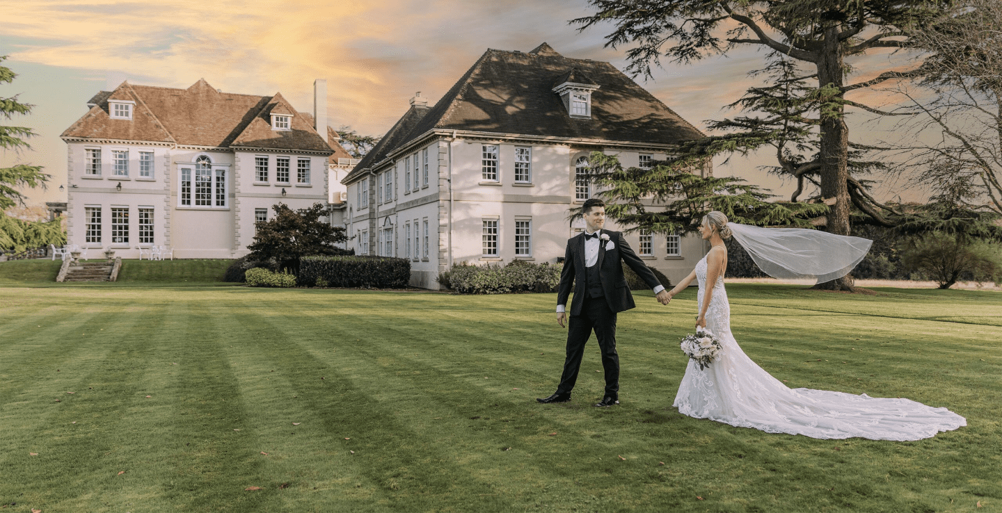 Bride and groom hold hands across the Brockencote Hall estate 