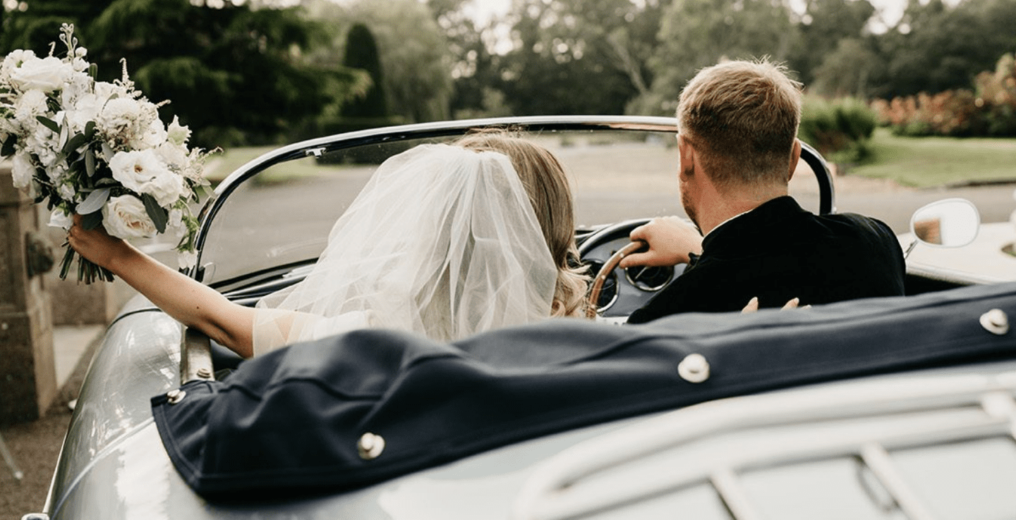 Luxury wedding venues Worcestershire - a bridge and groom cruise away in a silver vintage car, bride with bouquet in tow